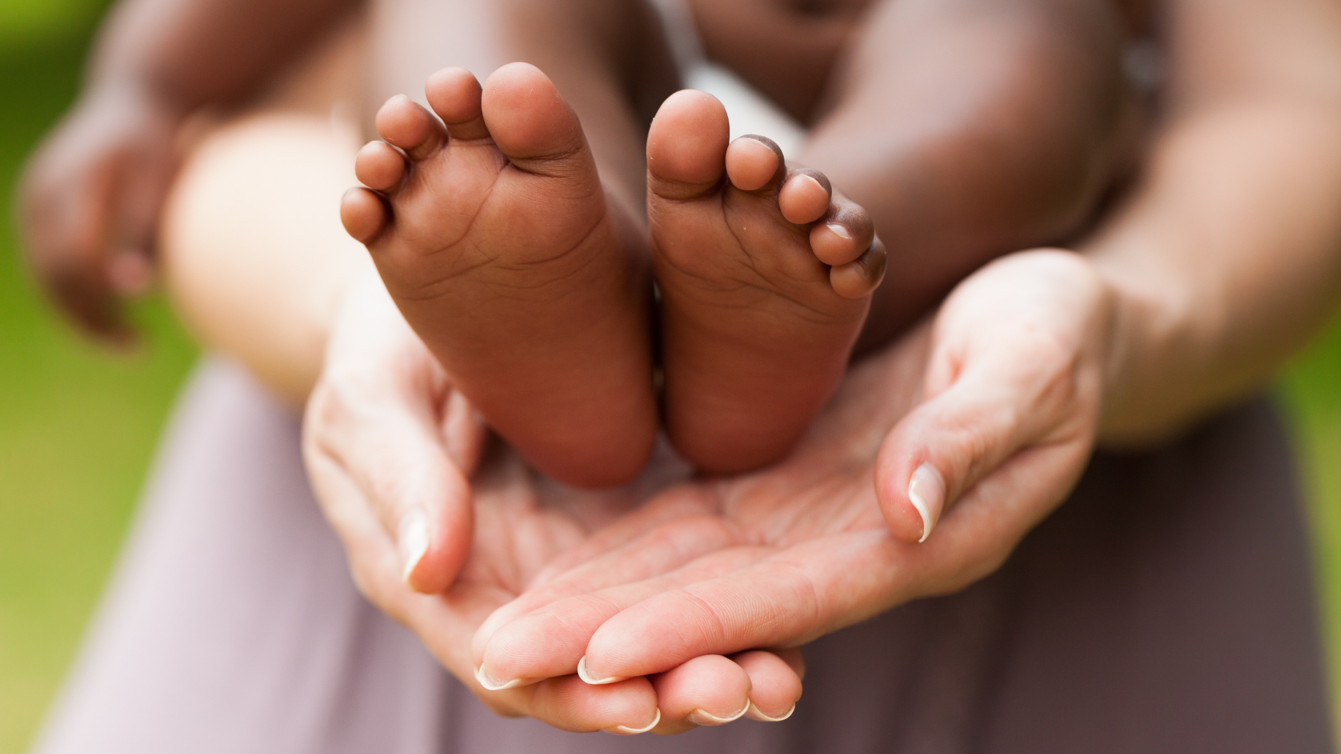 Adoption, causasian woman's hands holding dark skinned child